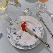 Royal Copenhagen | Blue Elements Plate, 22cm, featuring hand painted blue floral patterns, stacked with a butter knife and caviar, elegantly set on a dining table.
