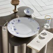 Royal Copenhagen | Blue Elements Plate, 28cm, with hand-painted blue floral pattern, set on a stylized table with matching bowl, glass, and utensils.