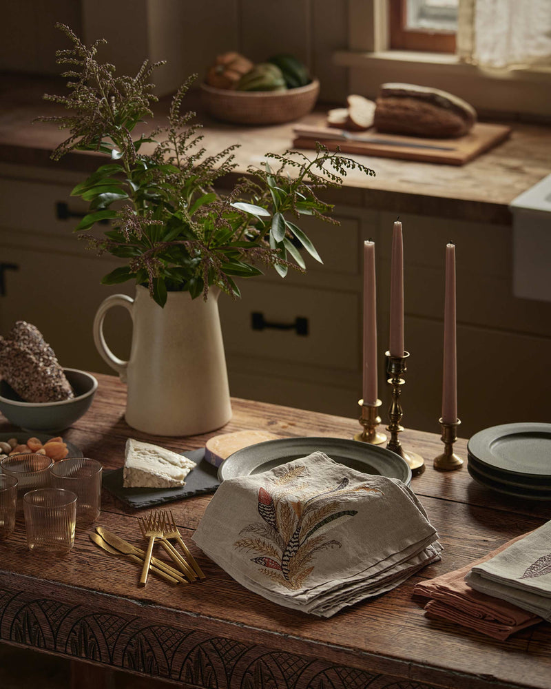 Coral & Tusk - Wheat Harvest Dinner Napkin on a rustic table with ceramics, candles, and cheese, embodying a farmhouse dining experience.