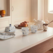 Royal Copenhagen Blue Fluted Plain Butter Dish elegantly displayed on a kitchen island, accompanied by matching china and fresh croissants, showcasing classic design and craftsmanship.