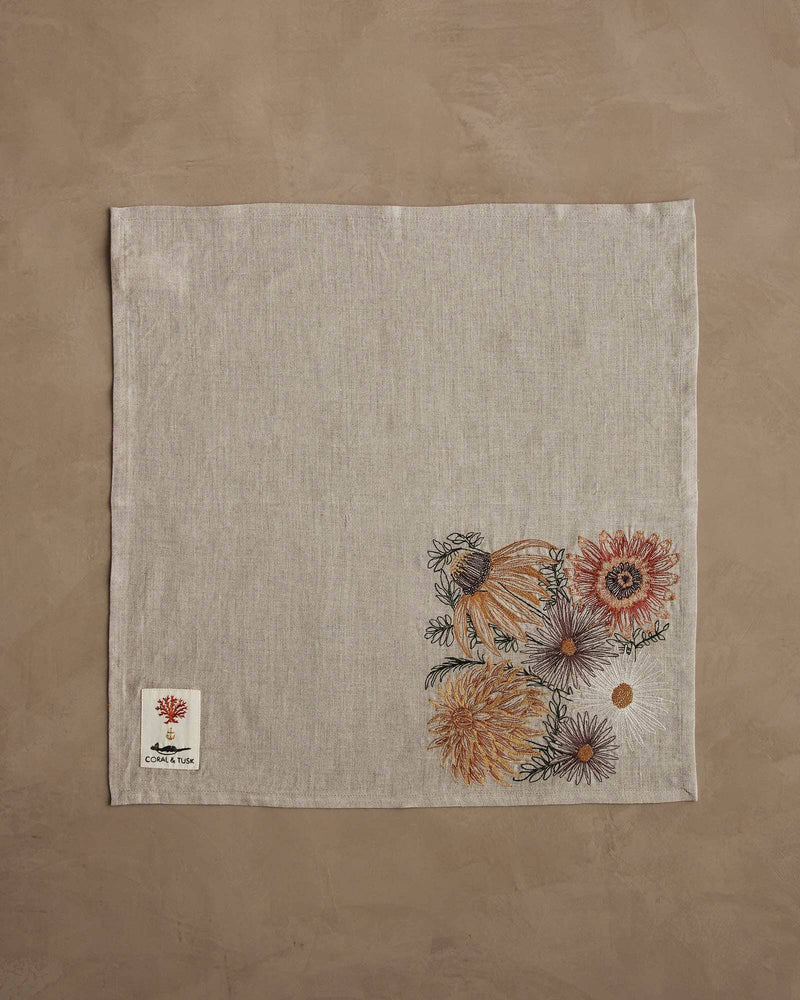 Coral & Tusk - Autumn Blossoms Dinner Napkin featuring embroidered wildflowers in autumn tones, showcasing mums, daisies, sunflowers. Includes a woven label. Measures 20 x 20.