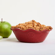 Emile Henry | Modern Classics Mini Pie Dish in red holds a golden-brown lattice apple pie with a whole green apple beside it, showcasing artisanal bakeware quality.