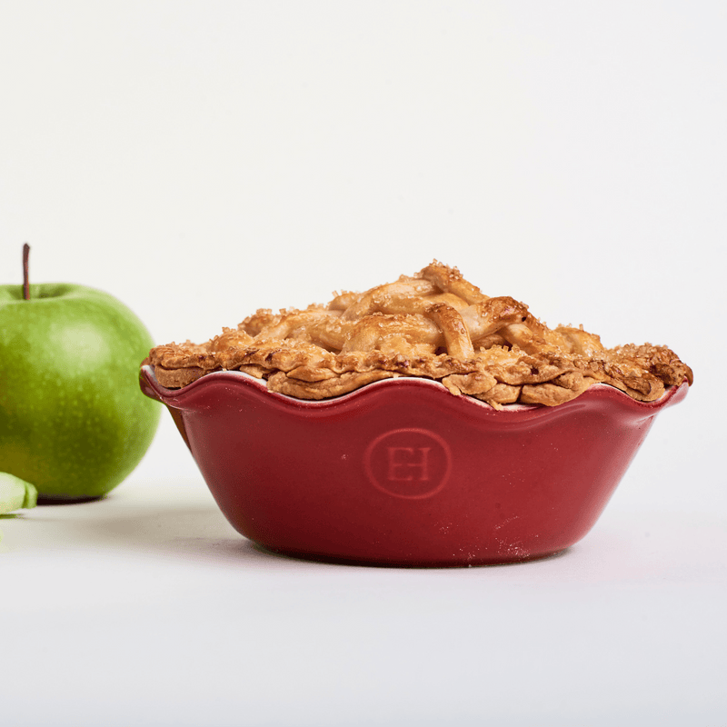 Emile Henry | Modern Classics Mini Pie Dish in red holds a golden-brown lattice apple pie with a whole green apple beside it, showcasing artisanal bakeware quality.