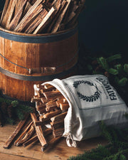 Farmhouse Pottery - Fatwood - 5lb. Bag spills onto a wooden surface, surrounded by pine cones and evergreens, ideal for effortless fire-starting in rustic kitchen settings.