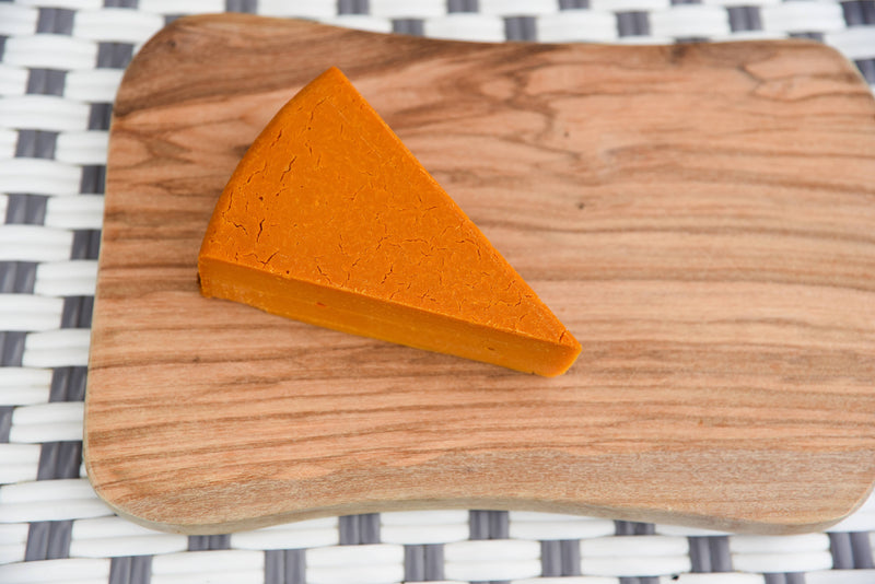 Rebel Cheese - Smoked Cheddar Plant Based - 5 oz, firm vegan cheese on a wooden board, ideal for slicing and cubing, from Athens Cooks.
