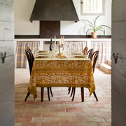 Caravan Home | 59 x 86 Forest Harvest Grey & Mustard Tablecloth set on a dining table, featuring rich fruit and foliage designs, enhancing a dinner setting.