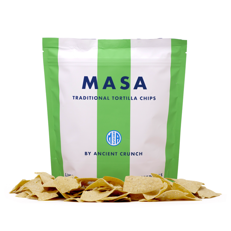Ancient Crunch | MASA Traditional Tortilla Chips, Lime in a white bag with chips in front, showcasing zesty flavors and handmade quality, ideal for sharing.