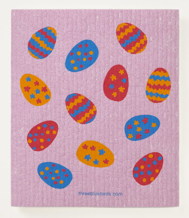 Three Bluebirds Swedish Dishcloth featuring colorful Easter egg designs on a pink mat, ideal for sustainable kitchen use, absorbs 20x its weight.