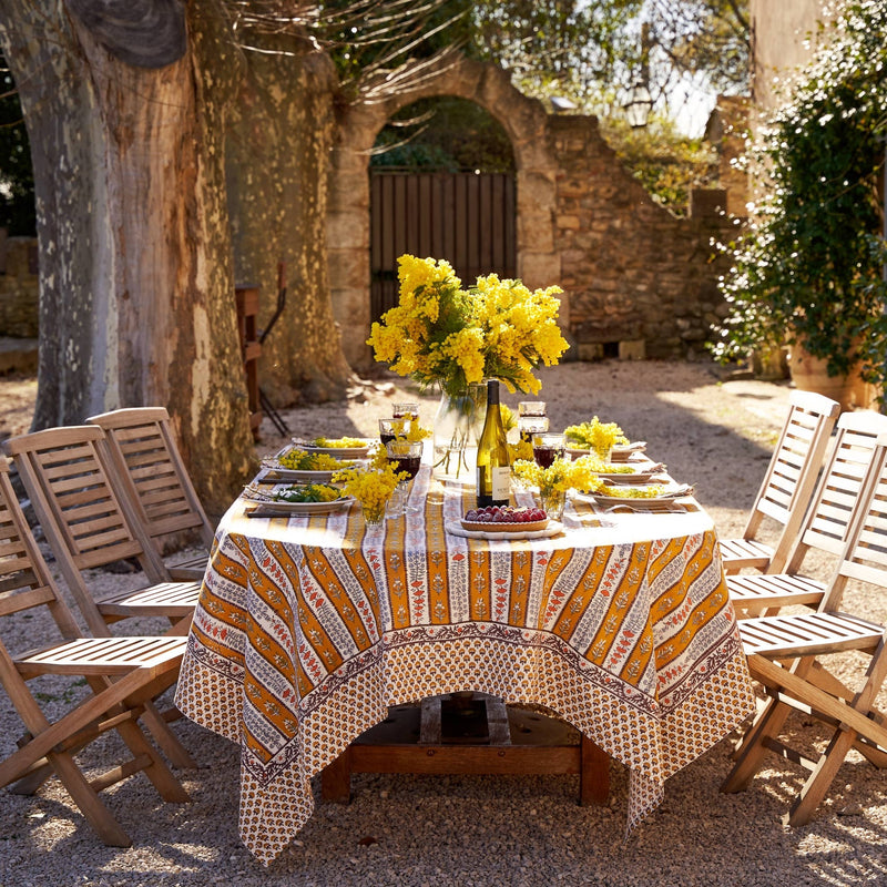 Couleur Nature - Provence Avignon Dijon & Blue Tablecloth: 71 x 106 draped on a wooden table with wine, flowers, and dessert in a charming courtyard.