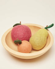 Handcrafted in Nepal, the Farmhouse Pottery - Felted Fruit Ornament: Pear and two other felt fruits sit in a light-wood decorative bowl.