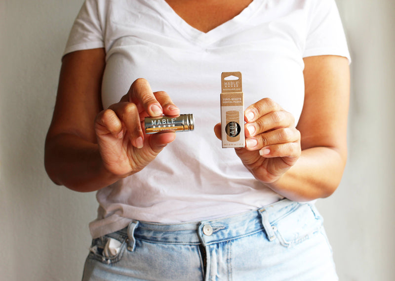 Person holding MABLE - Stainless Steel Floss Container and Zero-Waste Dental Floss box, showcasing eco-friendly, refillable, silk floss system for sustainable dental care.