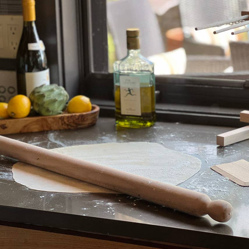 Italian Beechwood Rolling Pin and Dough Scraper Set displayed on a kitchen counter, showcasing its long, sturdy design ideal for pasta and dough preparation.