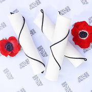 ATELIER SAUCIER - Cream Burlap Noir Napkins, set of 4, featuring soft burlap linen with black edging, styled with red anemones on a branded background.