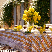 Couleur Nature - Provence Avignon Dijon & Blue Tablecloth: 71 x 71 on an outdoor dining table, adorned with mimosa flowers, place settings, and wine glasses in a sunlit garden.