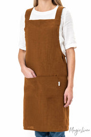Person wearing MagicLinen's Pinafore cross-back linen apron with twin front pockets, ideal for cooking or gardening, showcasing its unisex design and functional style.