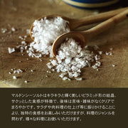 Wholesome Good - Maldon Sea Salt 8.5oz / 12: Single, featuring pyramid-shaped flakes on wooden spoons, ideal for enhancing dishes with crisp texture and pure saltiness.