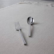 Zwiesel Fortessa | Arezzo Flatware Serving Set, Polished, featuring a sleek fork and tablespoon on a textured surface, exemplifying modern elegance and high-quality craftsmanship.