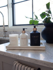 L'AVANT Collective - Fresh Linen Hand Lotion displayed in a glass bottle on a tray with candles, highlighting its luxurious, spa-like quality.