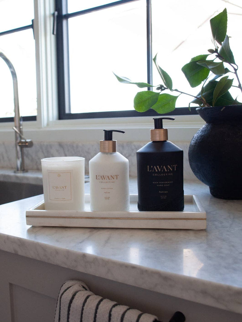 L'AVANT Collective - Fresh Linen Hand Lotion displayed in a glass bottle on a tray with candles, highlighting its luxurious, spa-like quality.