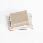 Gravesco Pottery - Soap Dish | White: Handmade ceramic dish with grooves, holding a speckled soap bar, offering unique craftsmanship from Indianapolis. Perfect for extending soap longevity.