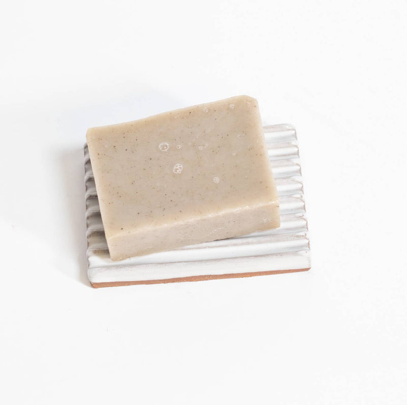 Gravesco Pottery - Soap Dish | White: Handmade ceramic dish with grooves, holding a speckled soap bar, offering unique craftsmanship from Indianapolis. Perfect for extending soap longevity.