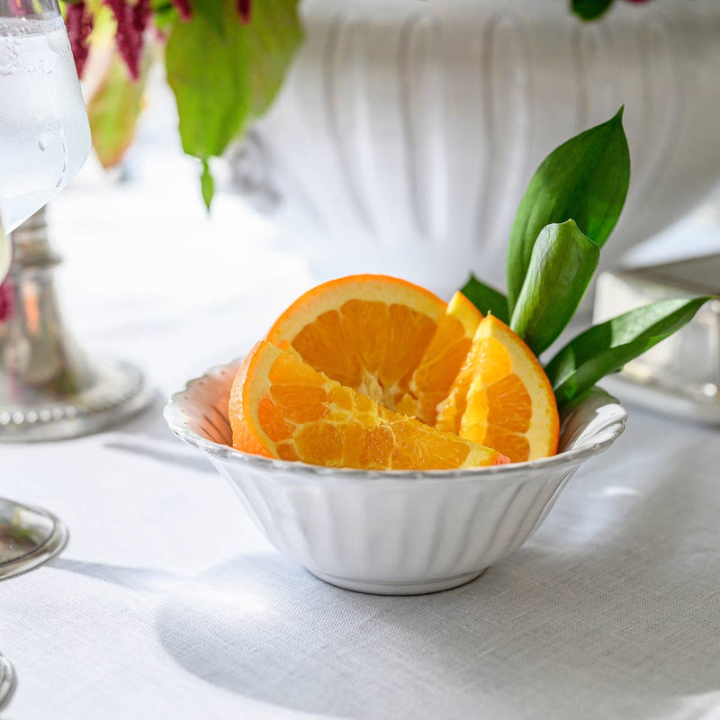 Arte Italica & Crown Linen Designs - Bella Bianca Beaded Cereal Bowl, elegantly crafted Italian stoneware, displayed with oranges, highlighting its delicate white glaze and unique design.