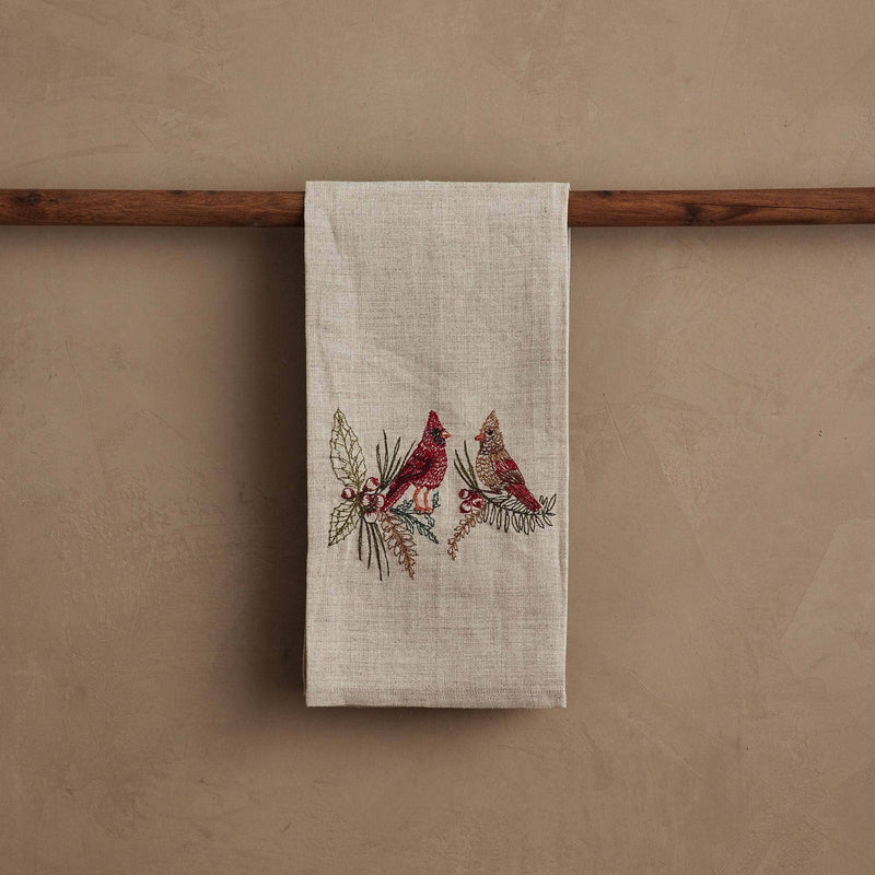 Coral & Tusk - Christmas Cardinals Tea Towel features embroidered cardinals on pine and holly, draped over a wooden rod, perfect for gifting.