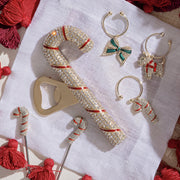 Joanna Buchanan Christmas Wine Charms displayed on white cloth, featuring festive designs like candy canes and bows, ideal for holiday gatherings.