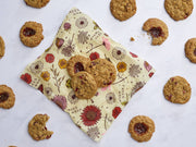 Bee's Wrap - Sandwich Wrap - Meadow Magic, Vegan Wax displayed with homemade oatmeal cookies, showcasing its reusable, eco-friendly design for preserving food.