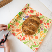 Bee's Wrap - New! Garden Party - Cut-to-Size Roll Wrap being cut with kitchen shears, showcasing its customizable, reusable nature in a kitchen setting.