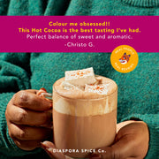 Diaspora Spice Co. Hot Cocoa Mix in a glass mug with marshmallows, highlighted by a customer review praising its sweet, aromatic flavor.
