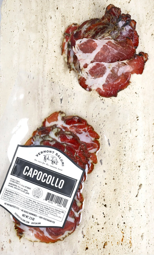 Vermont Salumi | Sliced Capocollo, vacuum-sealed, with marbled slices on stone surface, showcasing cured pork shoulder, aged with black pepper and coriander, ideal for charcuterie platters.