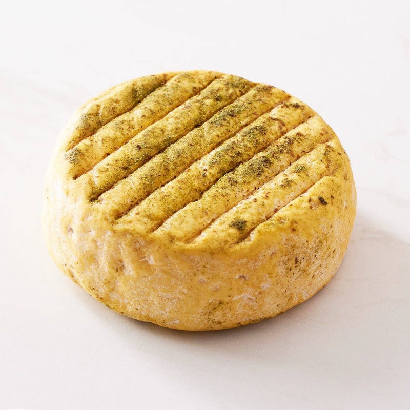 Perrystead Dairy - Atlantis: A semi-soft, wheel-shaped cheese with a yellowish rind, white bloom, and herb-dusted grooves, showcasing maritime and herbaceous flavors.