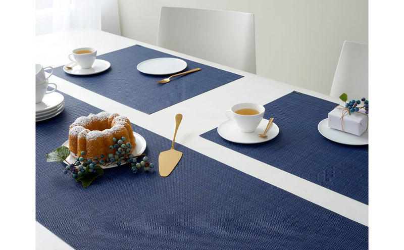 Chilewich Mini Basketweave Rectangle Placemats in Periwinkle elegantly set beneath a cake and tableware, showcasing refined texture and versatile dining style.