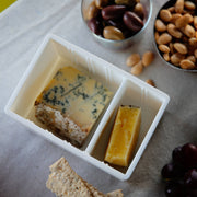 CapaBunga® Cheese Vault with blue and yellow cheese, surrounded by olives, peanuts, crackers, and grapes; ideal for artisan cheese storage.