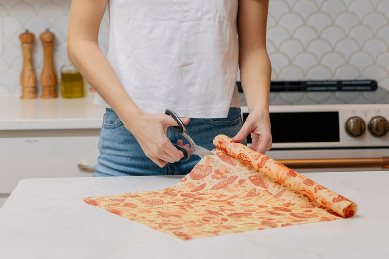 Bee's Wrap - Cut-to-Size Roll - Mushroom Magic, Limited Edition Print being cut on a kitchen counter, showcasing its versatility in sustainable, reusable food storage.