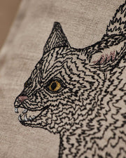 Coral & Tusk - Scaredy Black Cat Pillow: Linen cover hand-embroidered with a snarling cat, showcasing sparkling gold eyes, perfect for playful Halloween decor. Measures 12 × 16.