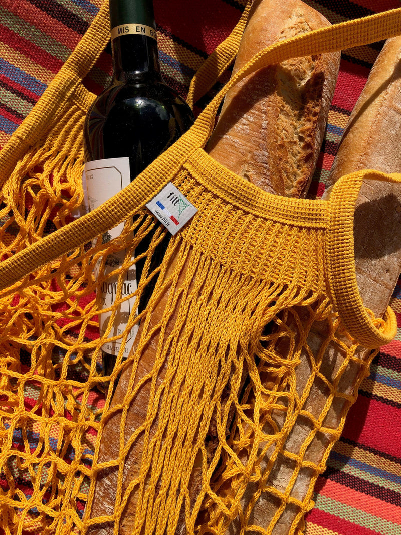 Filt | French Market Bags - Gold, featuring a woven cotton design, holds a wine bottle and baguette, ideal for eco-conscious shopping with durability and charm.