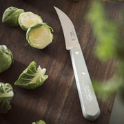 Opinel | Essential Small Kitchen Knife Sets Landscape: A gray-handled serrated knife on a cutting board with Brussels sprouts, highlighting its utility for precise kitchen tasks.