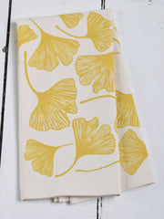 Hearth and Harrow - Ginkgo Leaf Tea Towel in organic cotton, showcasing mustard ginkgo-leaf pattern, folded on a wooden surface, emphasizing its oversized, eco-friendly design.