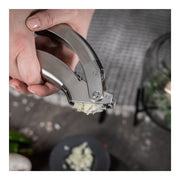 Kuhn Rikon | Epicurean Garlic Press in use, effortlessly crushing garlic with its ergonomic stainless steel design and easy-to-clean pullout sieve, showcasing superior cutting rather than bruising.