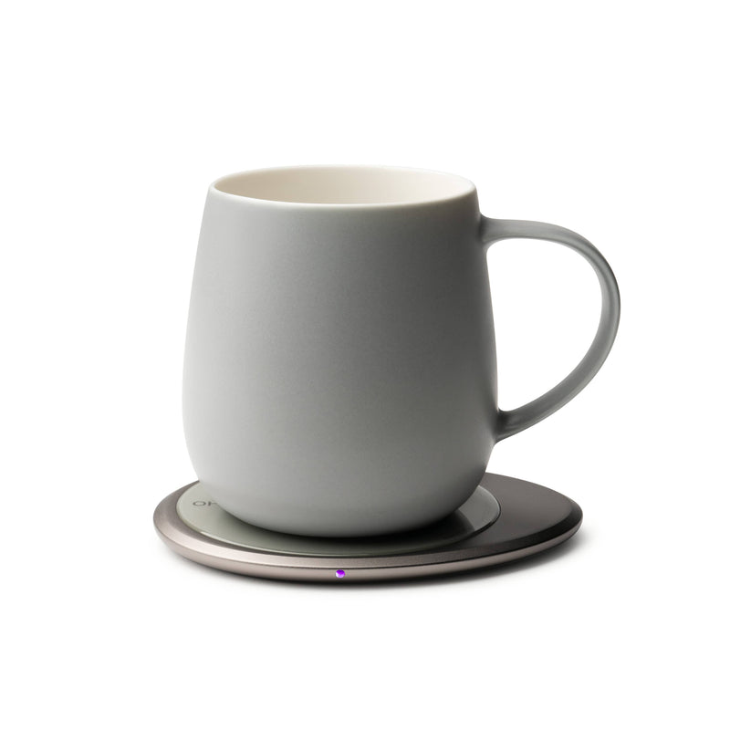 OHOM - Ui 3 Self-heating Mug Set: Jasmine White on a powered coaster, maintaining drink warmth and wirelessly charging phones, ideal for a refined kitchen experience.