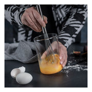 Kuhn Rikon | ESSENTIAL Ball Whisk whisking egg yolks in a glass bowl, showcasing its efficient design and versatility for seamless kitchen tasks.