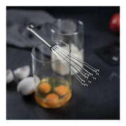 Kuhn Rikon | ESSENTIAL Ball Whisk rests on a glass of cracked eggs, showcasing its innovative design for efficient mixing and easy cleaning.
