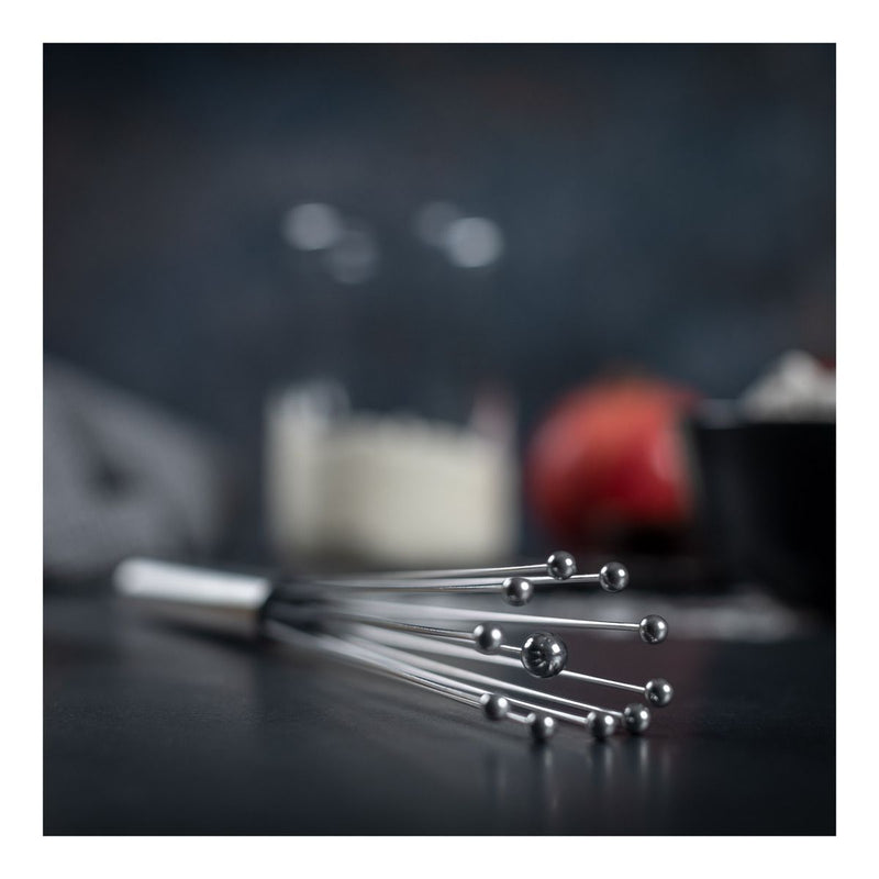 Kuhn Rikon | ESSENTIAL Ball Whisk on dark countertop, showcasing its sleek design ideal for creating perfect creams and sauces effortlessly.