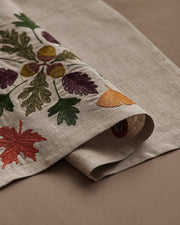 Coral & Tusk - Pressed Leaves Dinner Napkin featuring embroidered autumn leaves and acorns on natural linen, ideal for adding fall charm to your table setting.