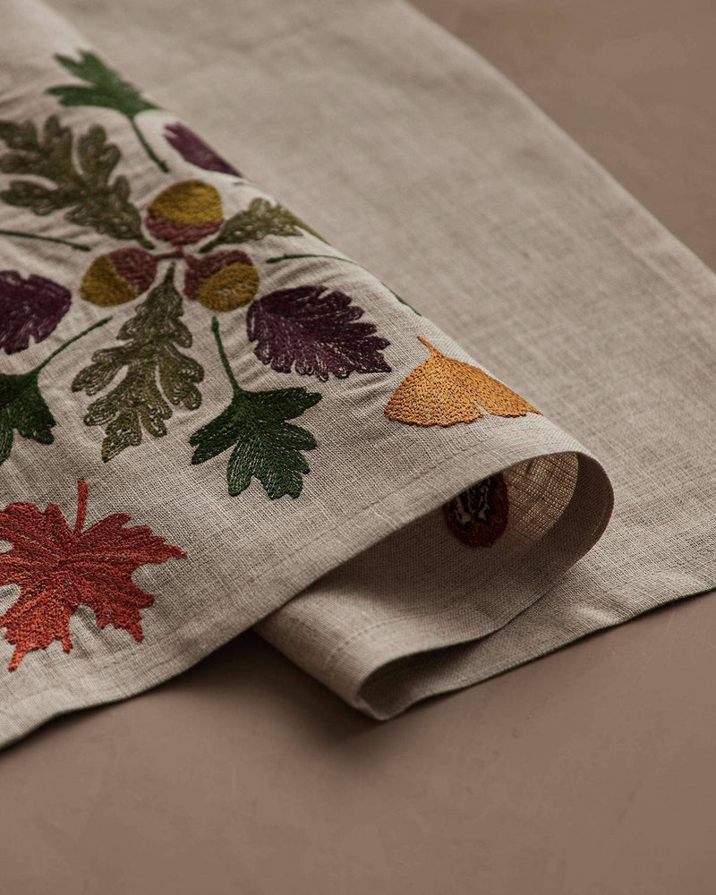 Coral & Tusk - Pressed Leaves Dinner Napkin featuring embroidered autumn leaves and acorns on natural linen, ideal for adding fall charm to your table setting.