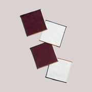 ATELIER SAUCIER - Clubhouse Cocktail Napkins: Set of 4 square fabric napkins, featuring burgundy corduroy and white textured sides, arranged diagonally, ideal for stylish entertaining.