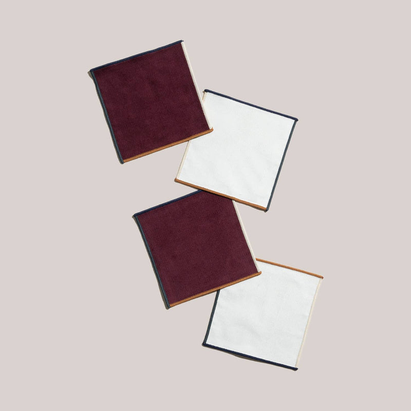 ATELIER SAUCIER - Clubhouse Cocktail Napkins: Set of 4 square fabric napkins, featuring burgundy corduroy and white textured sides, arranged diagonally, ideal for stylish entertaining.