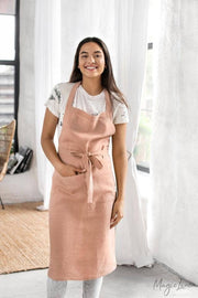 Woman in a charcoal grey linen bib apron with pockets, designed for cooking or gardening, exemplifying MagicLinen's stylish and functional unisex design.